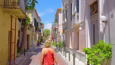 rear view of adult woman walking on narrow european street on sunny summer day in slow motion