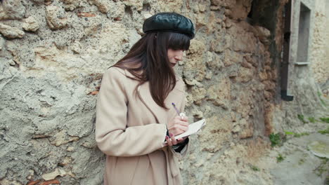 woman studying outdoor in her little hamlet while leaning on a wall