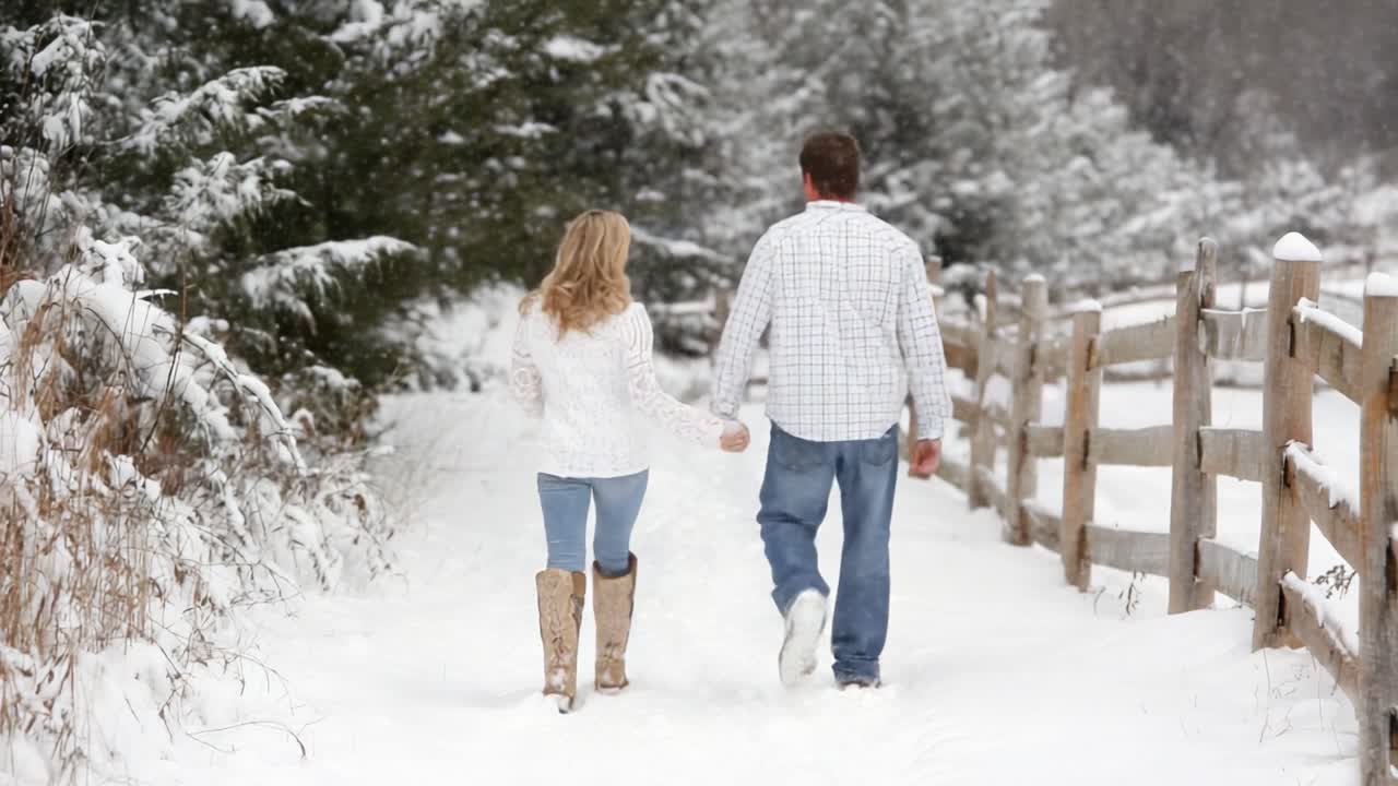 A Romantic Winter Walk: A Couple Strolls Hand in Hand Through a Snowy Landscape, Surrounded by Pine Trees and a Wooden Fence, Embracing the Beauty of Winter Together