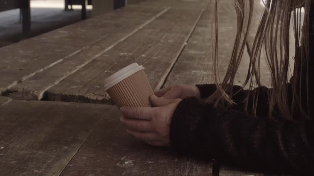 Hands holding a takeaway coffee to-go on table