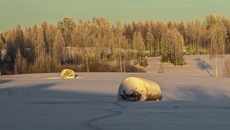 Lapso-De-Tiempo-De-La-Luz-Del-Sol-Dorada-Que-Pasa-Sobre-Fardos-De-Heno-Cubiertos-De-Nieve-Descansando-En-Tierras-De-Cultivo-De-Nieve-De-Invierno