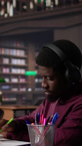 vertical video male student listening to ambient study music on headset and collecting data