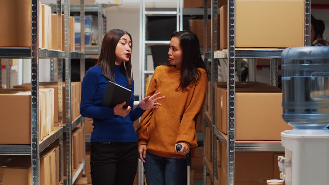 Two women talking in a warehouse with boxes