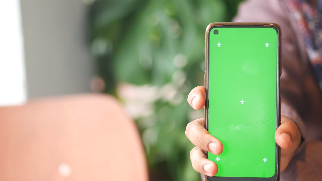 persona que sostiene un teléfono inteligente con pantalla verde