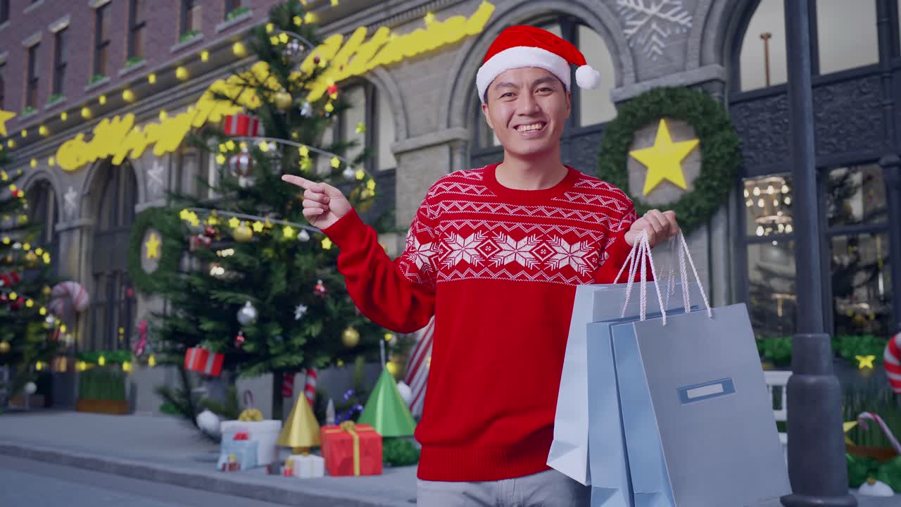 hombre asiático en traje de papá noel con las bolsas de compras sonriendo y señalando al lado mientras está de pie en la noche de navidad