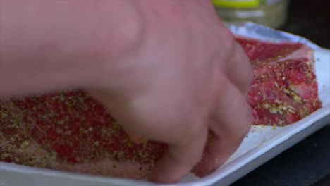 two hands turning spice covered rib eyes to cover the other side with sale and spices