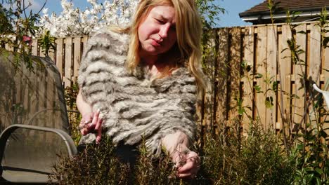 attractive woman picking fresh rosemary herbs from garden medium shot zoom in slow motion portrait