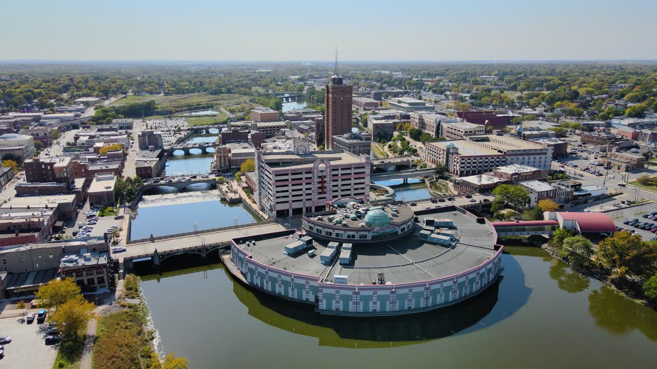 Drone footage capturing downtown Aurora, IL, a Chicago suburb in the Chicagoland area, near the river, buildings, and the Metra train line. Crane Up Day S