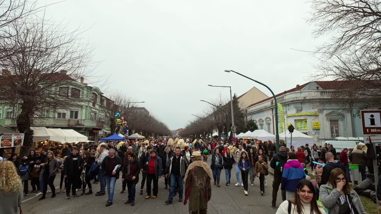 Main street of Mohacs during the Busó-walking festival, where the locals in scary sheepskin costumes and masks walk in the crowd among the visitors in Hungary.
