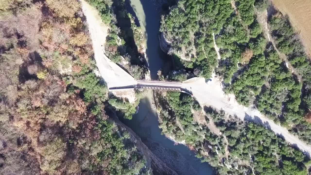 vista de pájaro mirando hacia abajo sobre un viejo puente oxidado que cruza el cañón de osumi