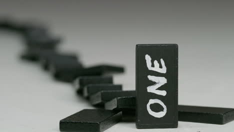 row of black dominoes with one in front with a word on it