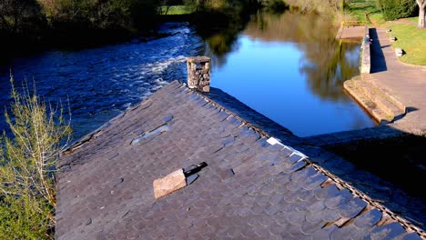 Aerial-Dolly-Back-View-Over-Destroyed-Slate-Roof-Of-Old-Cereal-Mill-In-Park-Beside-Tapia-River