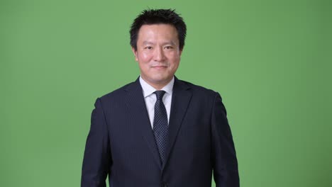 mature japanese businessman against green background