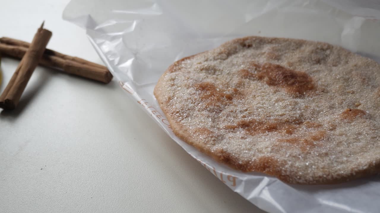 Traditional Spanish sugared olive oil biscuit on paper with cinnamon on the side