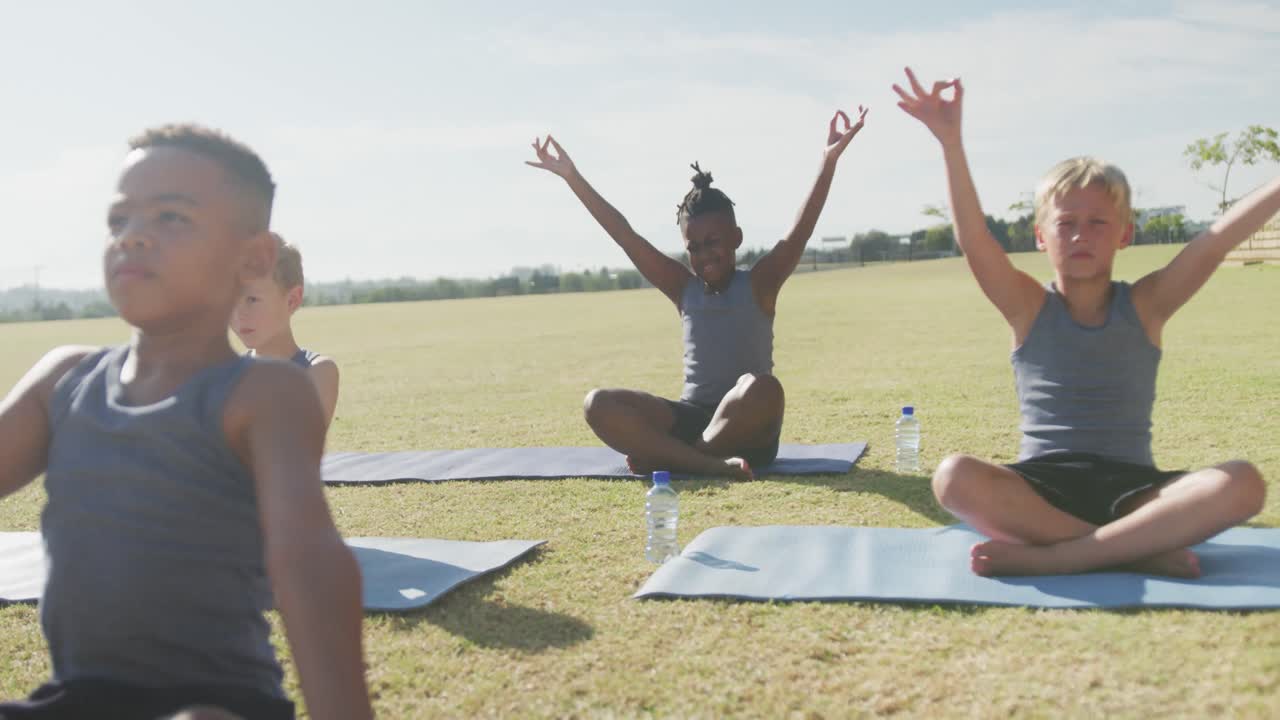 Video of diverse boys practicing yoga on mats on sunny day