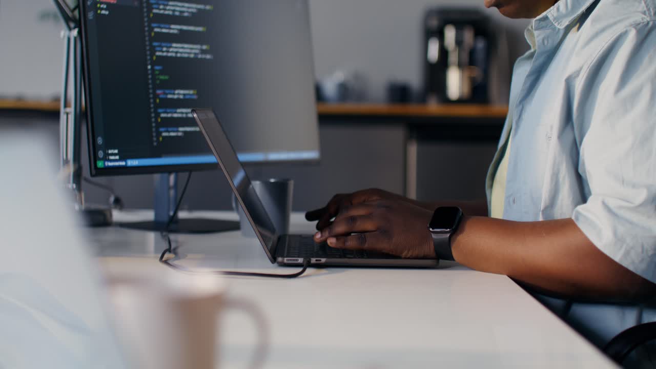 Programmer working on a laptop and computer monitor