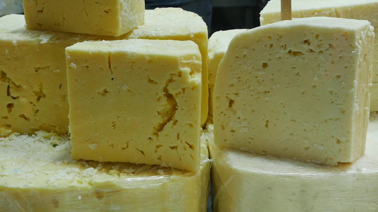 Blocchi di formaggio giallo fresco in esposizione al mercato