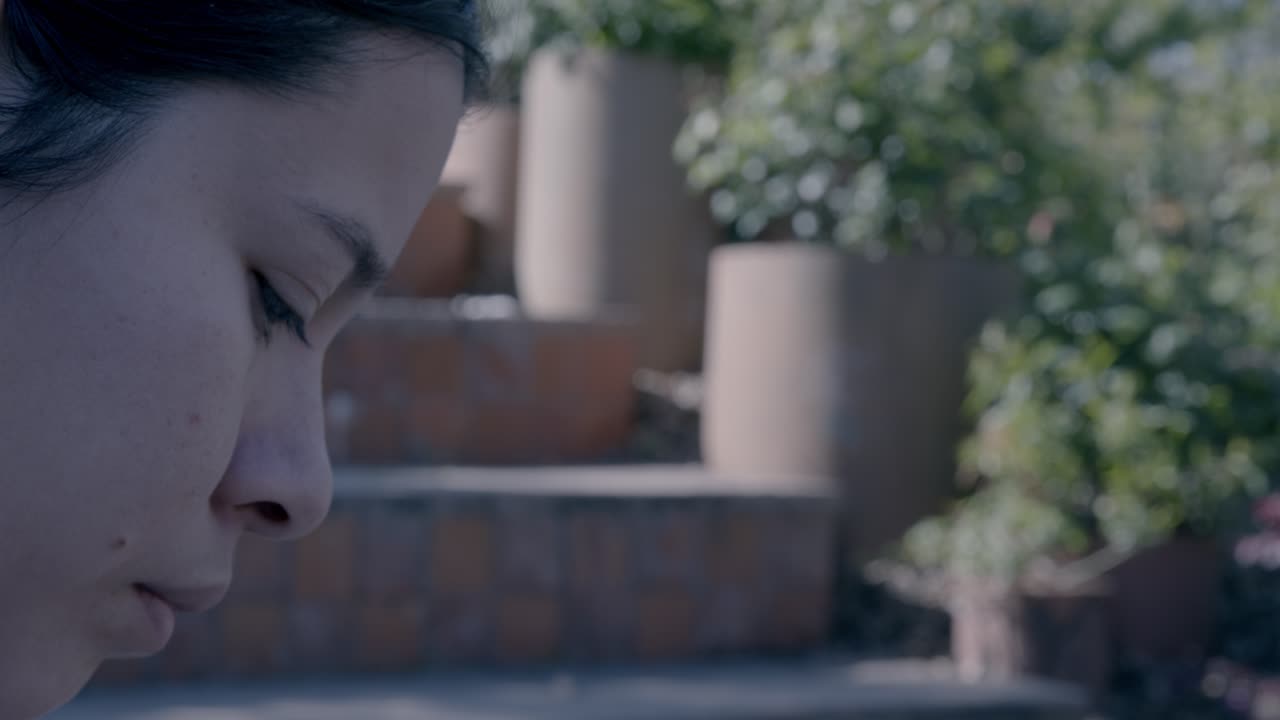 Blurry portrait of a person immersed in thought with a lush garden backdrop, soft focus creating a serene, introspective mood. The gentle, natural lighting highlights the tranquil ambiance