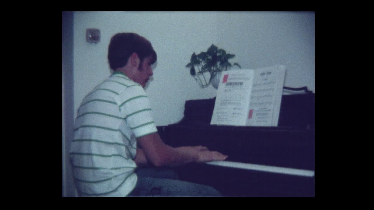 1971 Handsome teen boy plays piano
