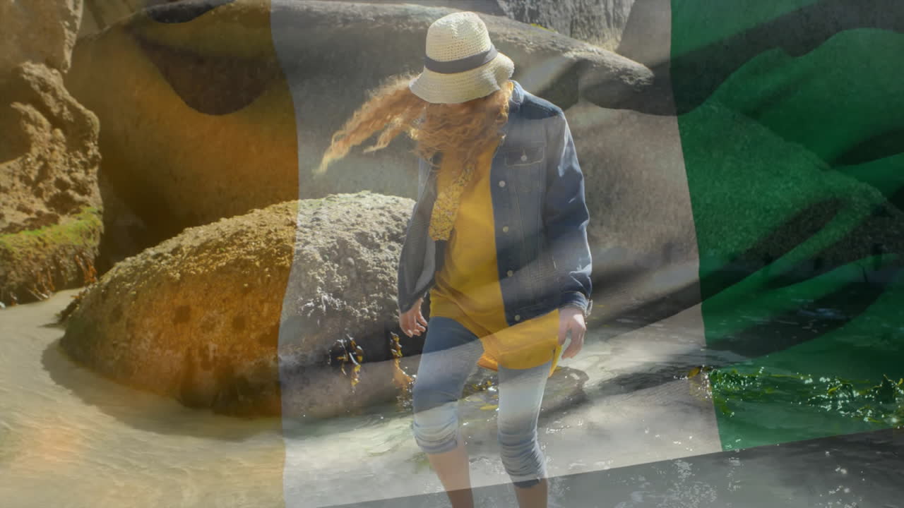 Walking on rocky beach, woman in denim jacket and hat with flag animation