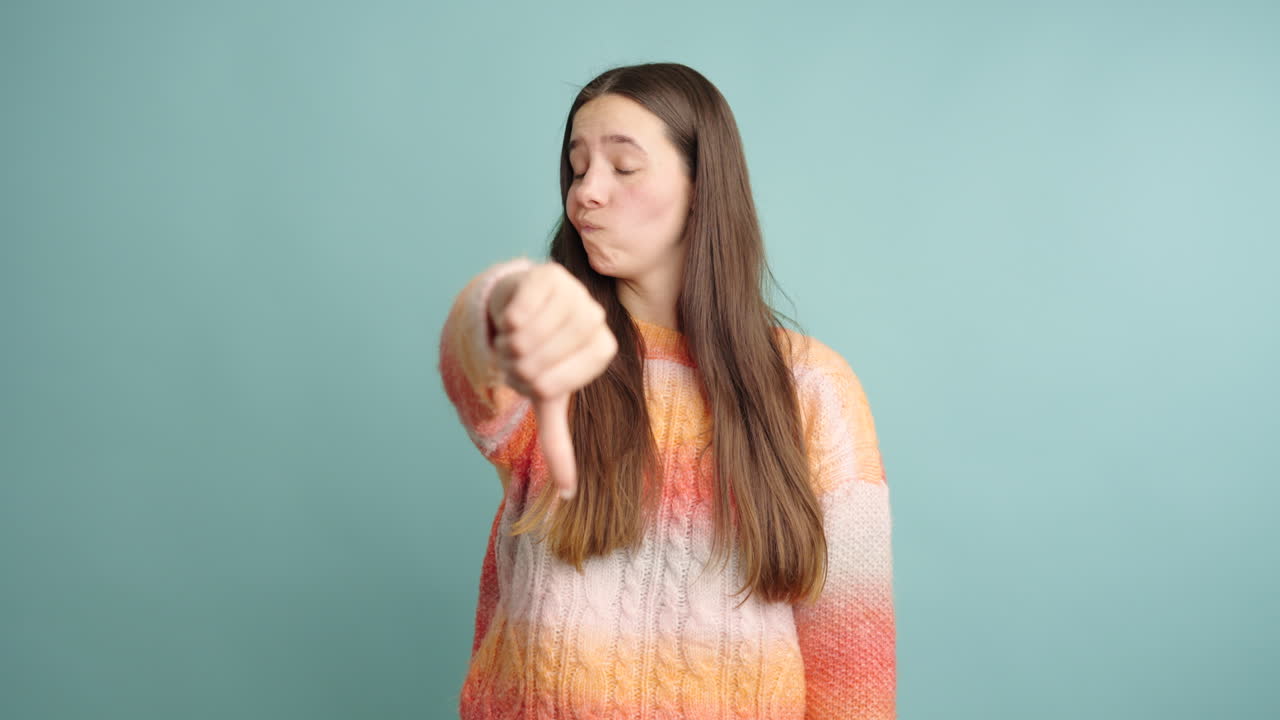 Young woman expressing disapproval with thumbs down gesture