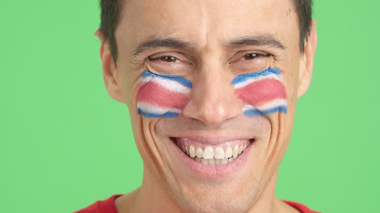 Man with a costa rican flag painted on the face smiling