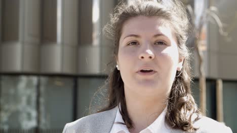 Front-view-of-focused-young-woman-talking-to-someone-on-street