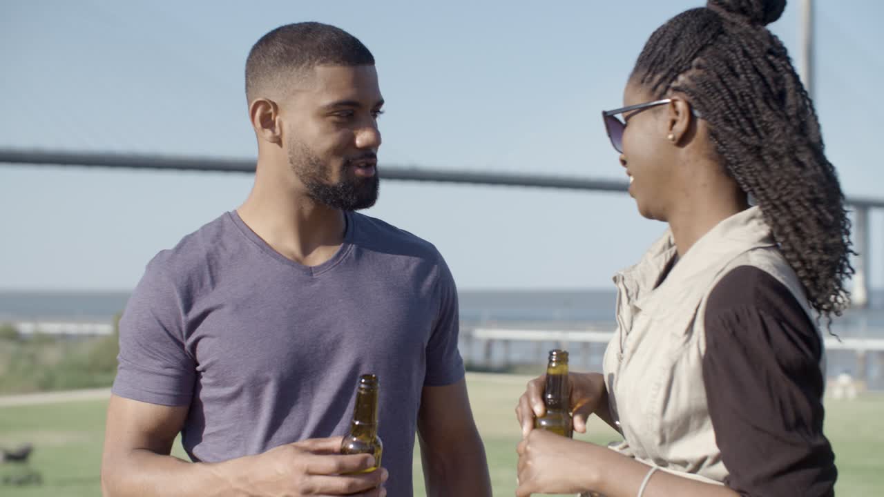 Happy African American couple talking while drinking beer.