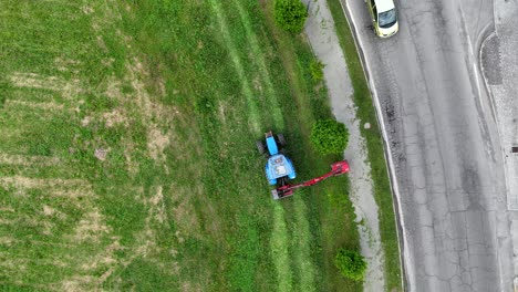 aerial view of blue agricultural machinery mowing lawn beside suburban roundabout in piacenza, northern italian cityscape