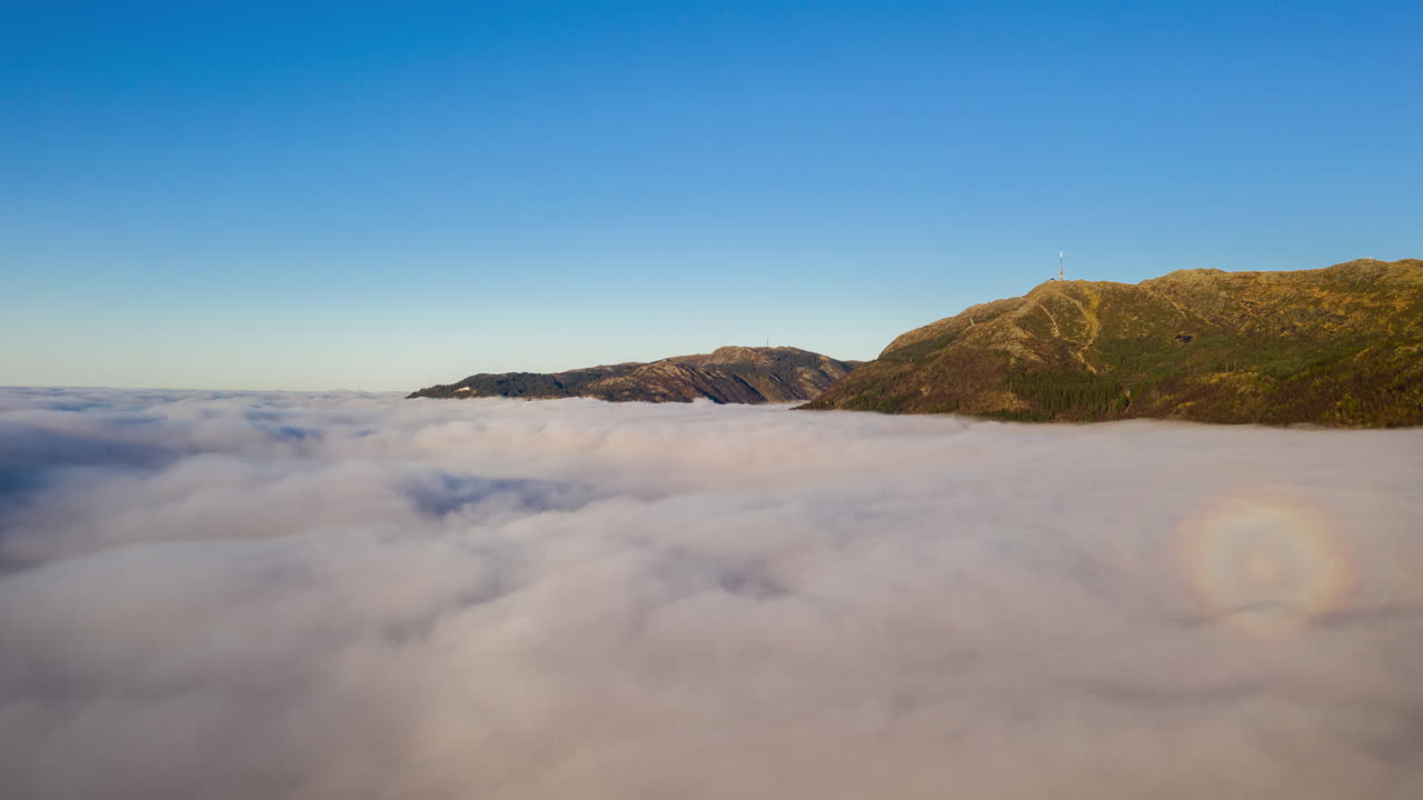 산 아래 계곡을 굴러가는 반전 구름 바로 위의 놀라운 항공 샷