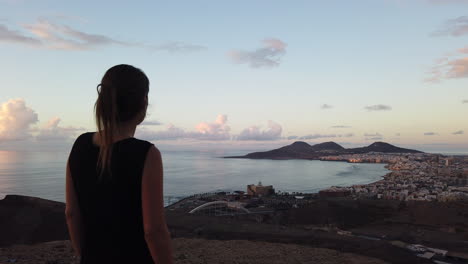 vista panorámica de la ciudad de las palmas y donde una mujer disfruta de las vistas a la playa de las canteras y al auditorio alfredo kraus