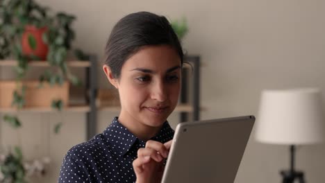 mujer de negocios india de pie sola en el interior trabajando en un dispositivo de tableta
