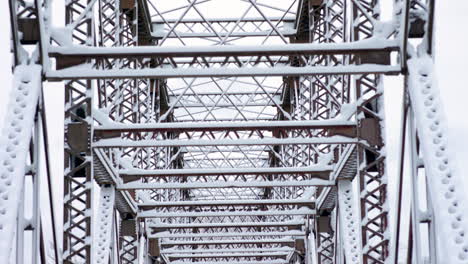 Handheld-tilt-down-of-a-snow-covered-truss-bridge