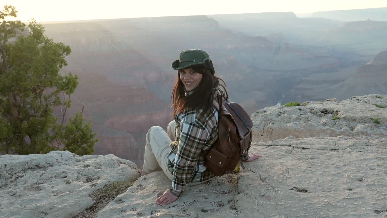 Donna escursionista sorridente con zaino al punto panoramico del Grand Canyon