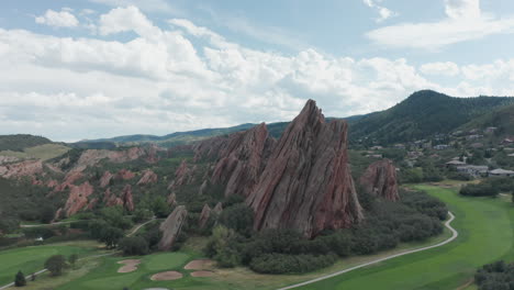 campo de golf de punta de flecha en littleton colorado con césped verde, rocas rojas y cielos azules