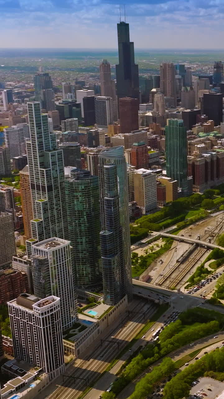 Huge green park surrounded by the beautiful skyscrapers. Aerial perspective on the spectacular scenery of Chicago city. Vertical video