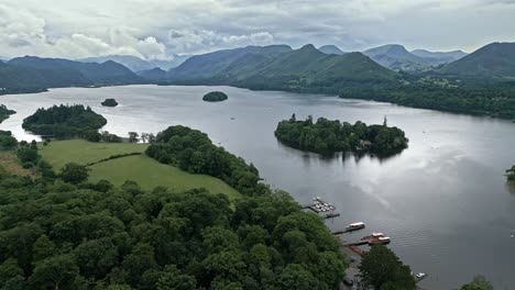 aerial footage of a island and house derwentwater, keswick, a calm lake with river boats and a stormy sky