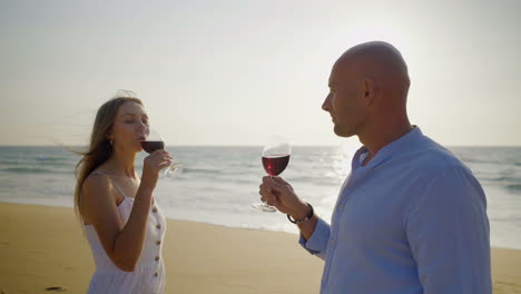 young couple drinking wine on beach