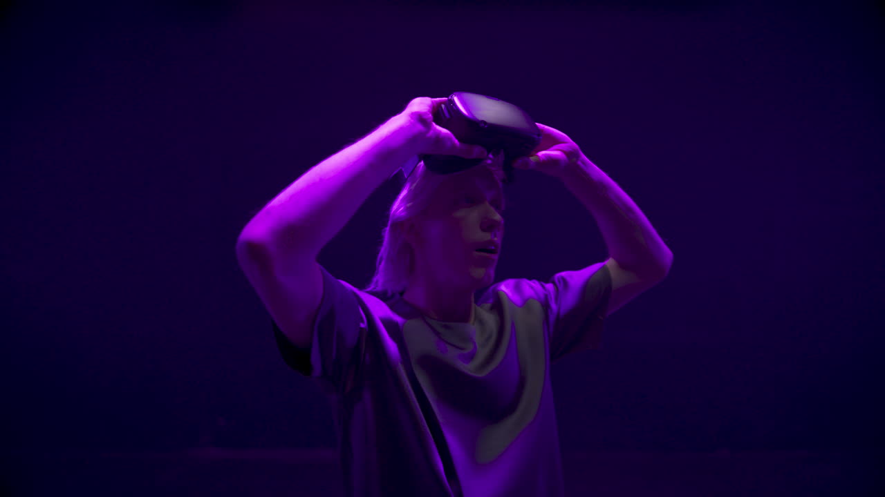 Gamer taking virtual glasses off in neon cyberspace closeup. Impressed guy look