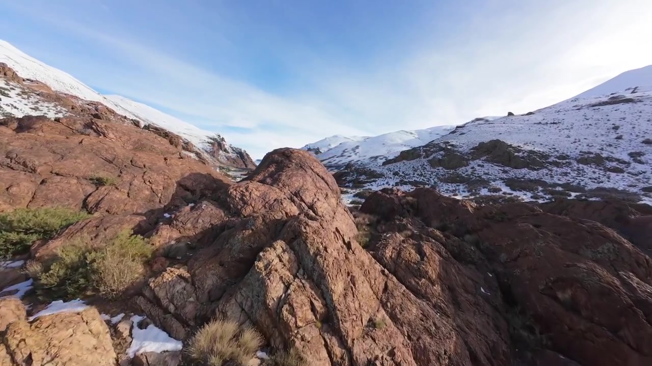 Strada del passo di montagna di Paso Pehuenche all'inizio dell'inverno, con cime parzialmente innevate e fiume. Planata aerea FPV