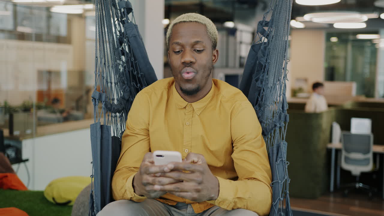 Man using smartphone in a hammock in modern office