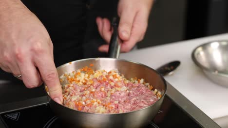 chef preparando una mezcla de carne y verduras en una sartén