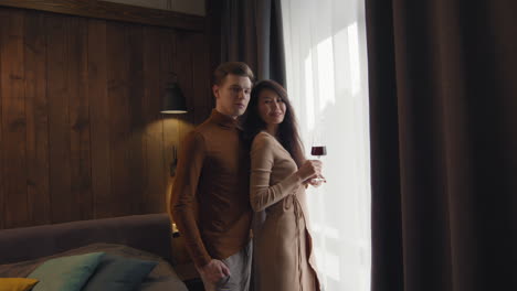 una pareja disfrutando del vino junto a la ventana en un dormitorio acogedor