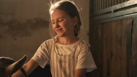 girl interacting with a goat in a barn