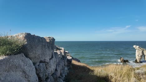 the calm waters of the sea of azov lap against rocky formations as the autumn sun shines brightly over the picturesque coastline of crimea