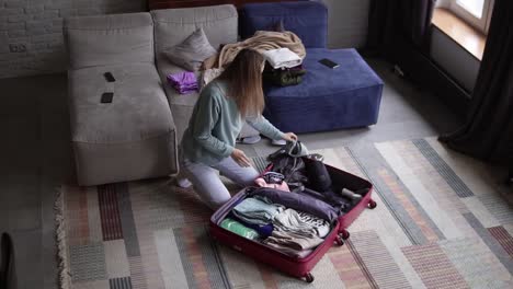 a woman in a hotel room puts things in a suitcase