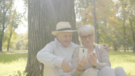 senior couple using smartphone in park