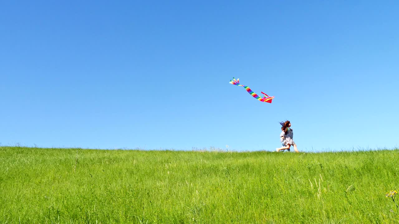 아이들은 날아다니는 kite와 함께 녹색 언덕을 내려 달립니다.