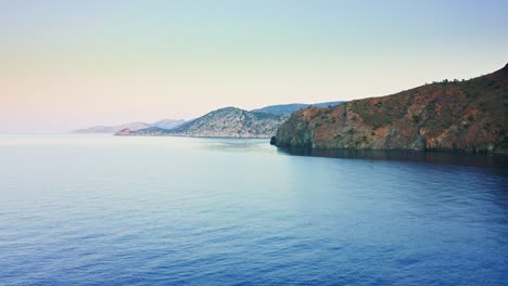 drone flight towards rock spit above calm sea surface