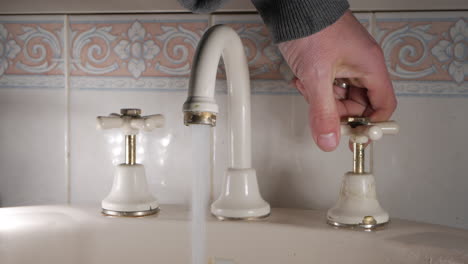 handyman tests bathroom tap after replacing washer